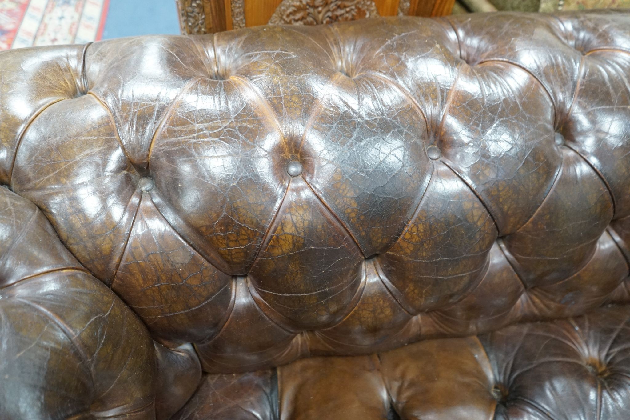 An early 20th century Chesterfield settee upholstered in deep buttoned brown leather, length 200cm, depth 90cm, height 72cm